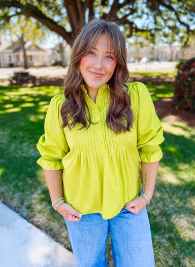 Bright colored blouse with pleated front panel.